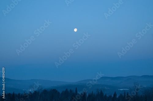Landscape view of Vermont during sunrise with the moon and a beautiful forest