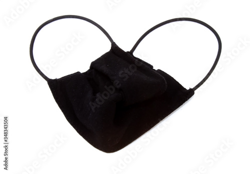 black medical mask folded in the shape of a heart lies on a white background