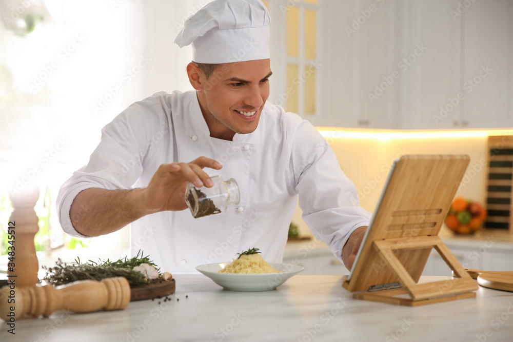 Chef with tablet cooking at table in kitchen Chef with tablet cooking at table in kitchen