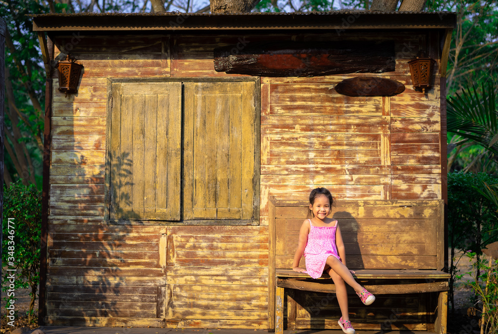 little asian girl sitting in front of home in countryside little asian girl sitting in front of home in countryside