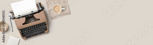 writing themed conceptual home office banner or header with mocca colored / brown vintage / retro typewriter on a beige desk - flat lay / top view