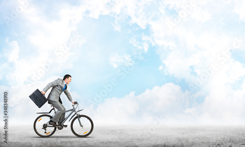 Man wearing business suit riding bicycle outdoor.