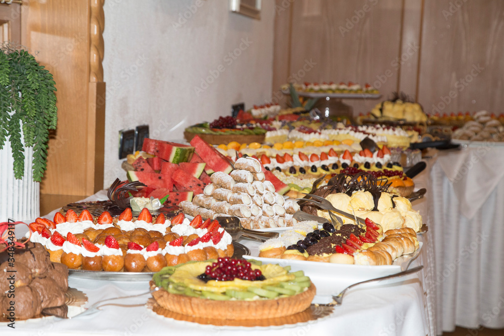 buffet with sweets. fruits and other sweets on dessert table. Rows of tasty looking desserts in beautiful arrangements. Sweets on banquet table - picture taken during catering event