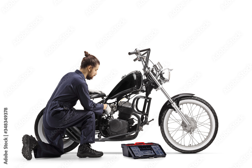 Motorcycle mechanic with a tool box repairing a chopper motorbike Motorcycle mechanic with a tool box repairing a chopper motorbike