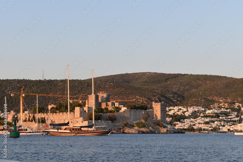 Boats are sailing in from of the Bodrum Castle while it is under renovation