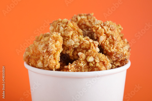 Bucket with yummy nuggets on orange background, closeup