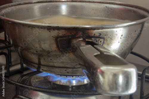 Iron pan boiling some water with pasta on a stove with the fire on