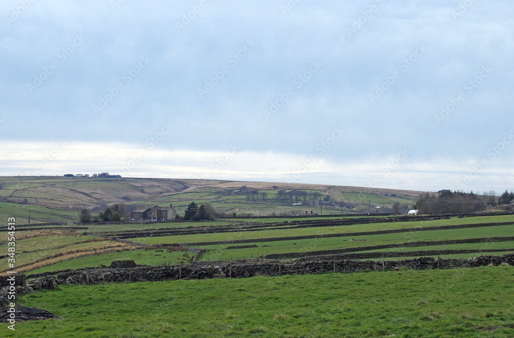 west yorkshire landscape with fields surrounded by stone walls with farmhouses and rolling moorland hills in the distance