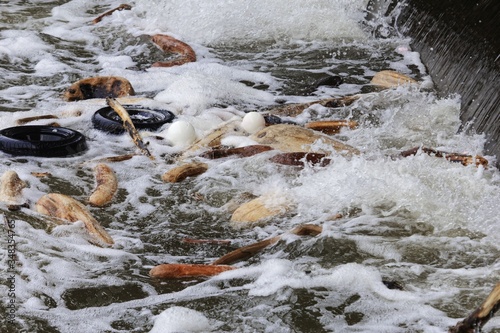 Triftwood, plastic waste and old tires in a river photo