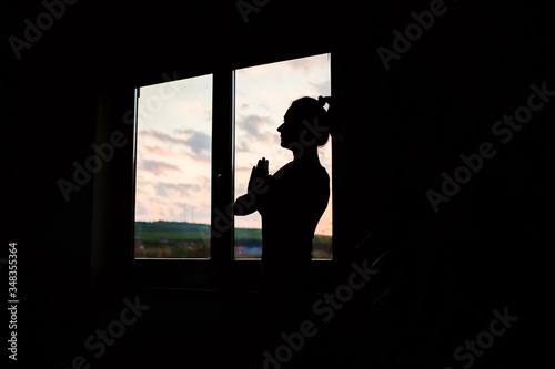 woman silhouette in yoga pose by window at sunet © Melinda Nagy