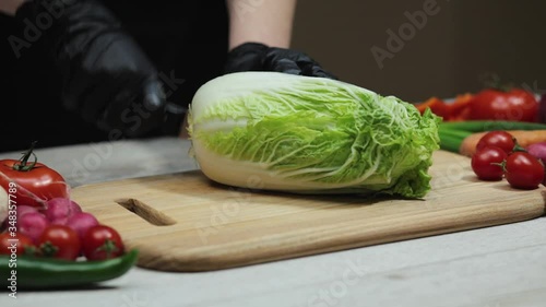 Female chef chops cabbage on the cutting board at the kitchen