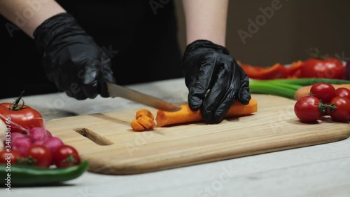 Woman cutting carrot on board in the kitchen, closeup