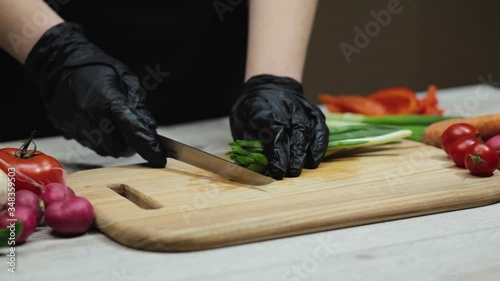 Close up of female chef who cutting green onion on board in the kitchen