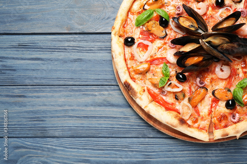 Tasty pizza with seafood and fresh basil on blue wooden table, top view. Space for text