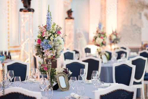 decor in the restaurant , floristic decoration of the festive table, a large vase with bright flowers, a festive dinner in honor of the wedding, table setting before dinner