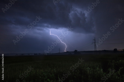 Lightning bolts strike from a thunderstorm at night. Thunderstorm in the field. Spring and summer storm. Danger nature.