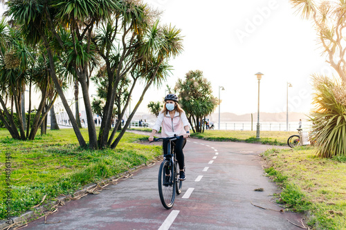 Wallpaper Mural Portrait of a woman with protective safety mask on her face riding a bike on a bike path in the city on a sunny day. Torontodigital.ca