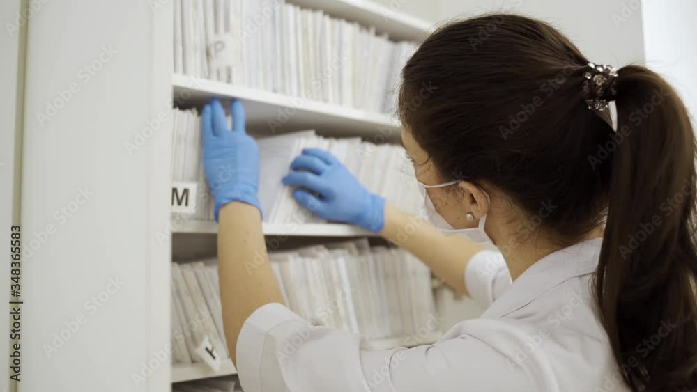 Masked Doctor searches for medical documents in new modern clinic during quarantine Masked Doctor searches for medical documents in new modern clinic during quarantine