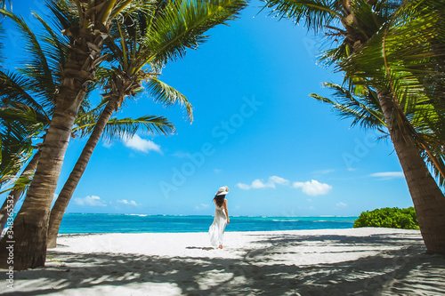 Woman enjoying sunny day on the tropical caribbean sandy beach landscape with turquoise sea and blue sky 