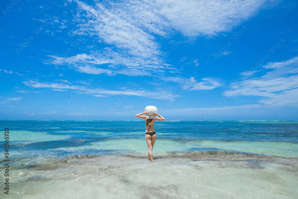 Woman enjoying sunny day on the tropical caribbean sandy beach landscape with turquoise sea and blue sky Woman enjoying sunny day on the tropical caribbean sandy beach landscape with turquoise sea and blue sky