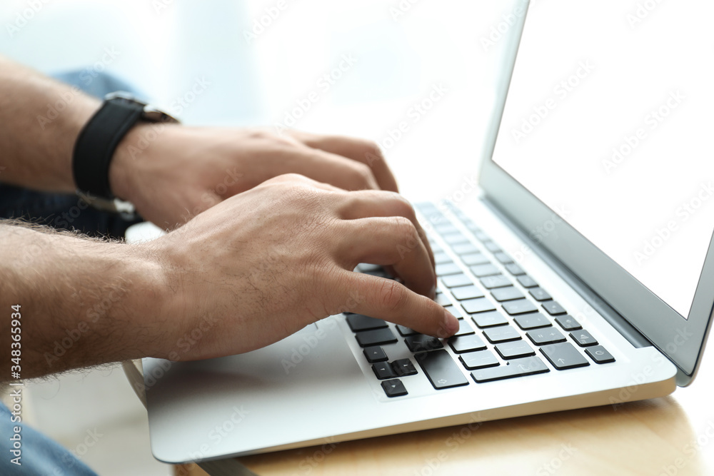 Man working on modern laptop at wooden table indoors, closeup Man working on modern laptop at wooden table indoors, closeup
