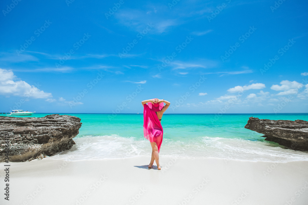 Woman enjoying sunny day on the tropical caribbean sandy beach landscape with turquoise sea and blue sky Woman enjoying sunny day on the tropical caribbean sandy beach landscape with turquoise sea and blue sky