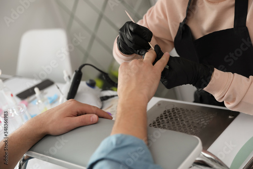 Professional manicurist working with client in beauty salon, closeup photo