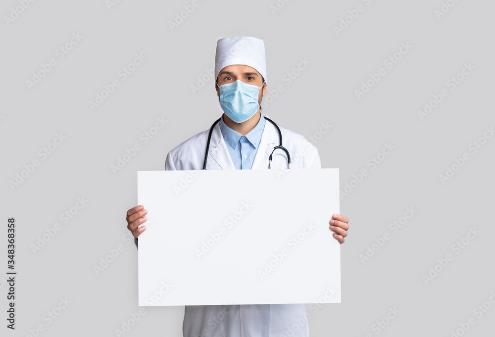 Doctor in protective wear with empty white signboard Doctor in protective wear with empty white signboard