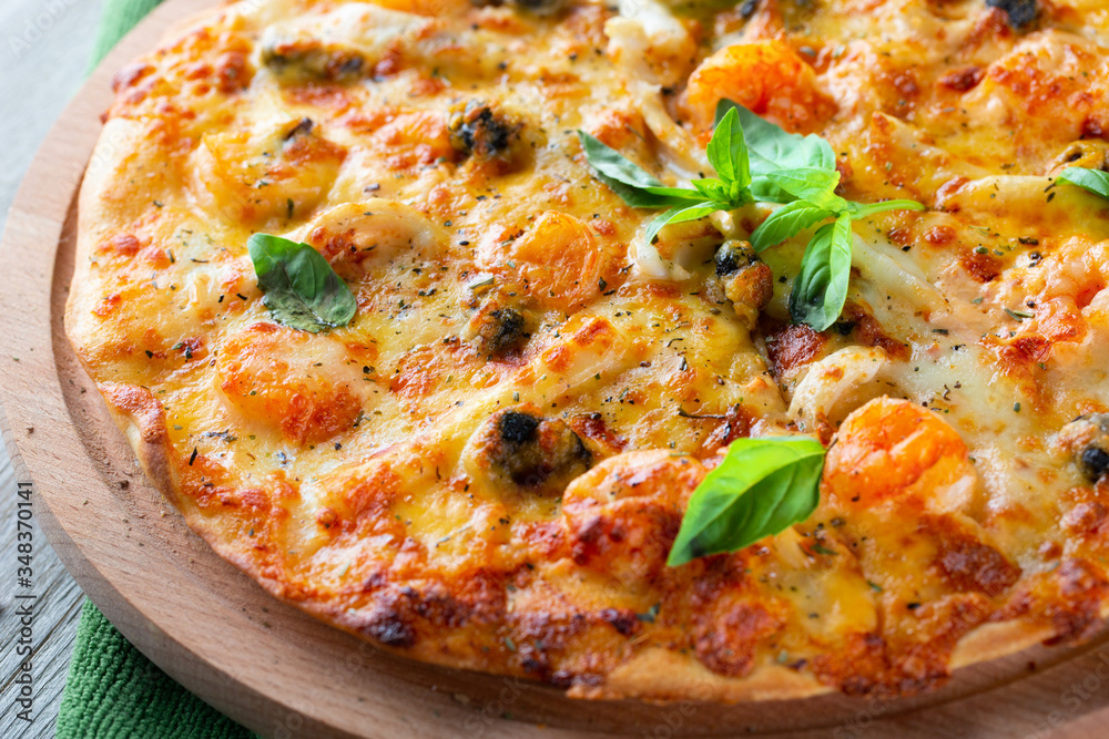 Seafood thin tasty pizza with shrimps, mussels and basil on wooden background Seafood thin tasty pizza with shrimps, mussels and basil on wooden background
