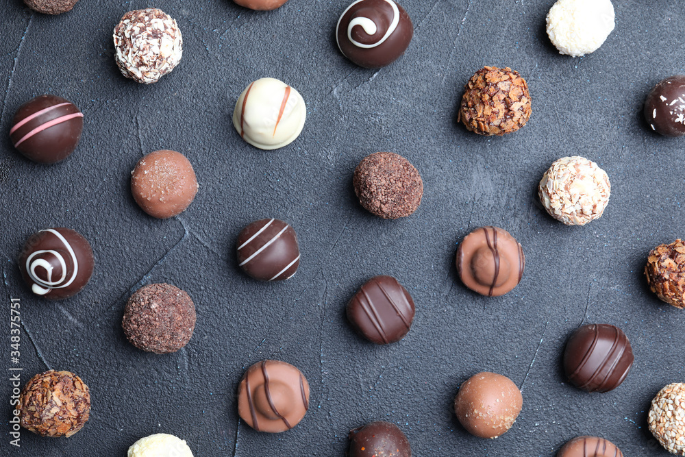 Different tasty chocolate candies on black table, flat lay