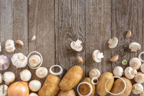 Mushrooms, potatoes and onion rings with garlic on a wooden background. Template for the text.