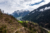Aerial view of valley with green slopes of the mountains of Italy cloudy weather, Trentino, The trees tumbled down by a wind, huge clouds over a valley, green meadows, Dolomites on background