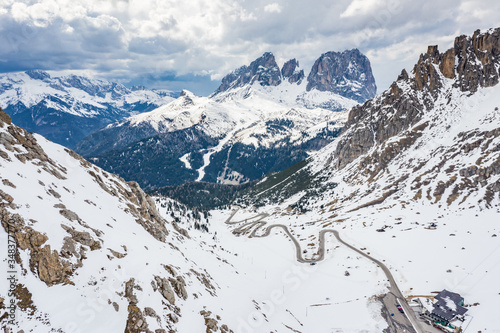 Aerial view of twisting road in the mountains of Italy, is serpentine among the snow-covered hills, is famous place among skiers and fans to understand a known by sports cars, mountains peak