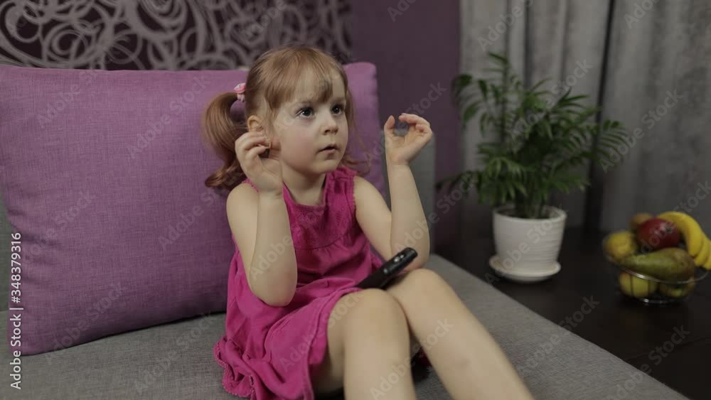 Little child sitting while watching TV. Scared kid girl watch horror movie Little child sitting while watching TV. Scared kid girl watch horror movie
