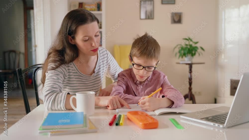 modern mother and her son sitting at the desk and writing lesson from laptop Spbas. mom parent helps child do homework. pupil schoolboy on distant education learning schooling. quarantine modern mother and her son sitting at the desk and writing lesson from laptop Spbas. mom parent helps child do homework. pupil schoolboy on distant education learning schooling. quarantine