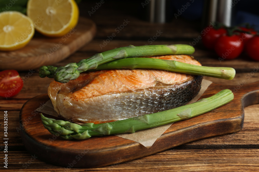 Tasty salmon steak served with asparagus on wooden table Tasty salmon steak served with asparagus on wooden table