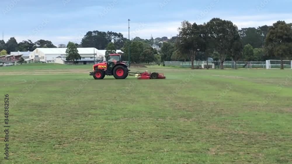 Lawn mowing vehicle being driven across a green grassy field during the daytime in Auckland New Zealand