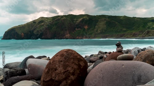 Time lapse of the sea with strong waves crashing to the rocky beach and the tall cliffs photo