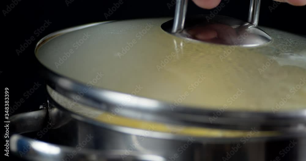 Man's hand removes lid from the pot of boiling potatoes. Man's hand removes lid from the pot of boiling potatoes.