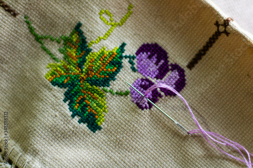 Cross-stitch art of purple grapes made with various colors on cloth
