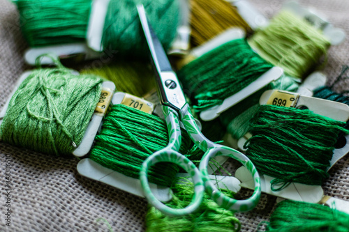 Collection of green colors of threads with a green scissors on a cloth