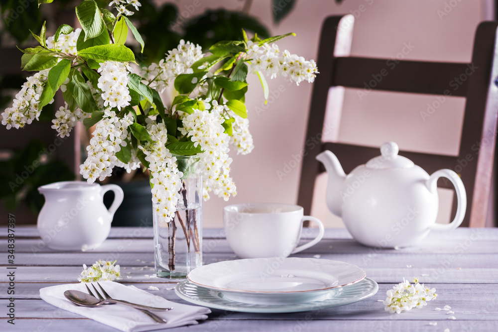 spring table setting with white flowers, plates with fork and knife on the white napkin spring table setting with white flowers, plates with fork and knife on the white napkin