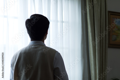 Side view of a young thinking businessman standing by an indoor window