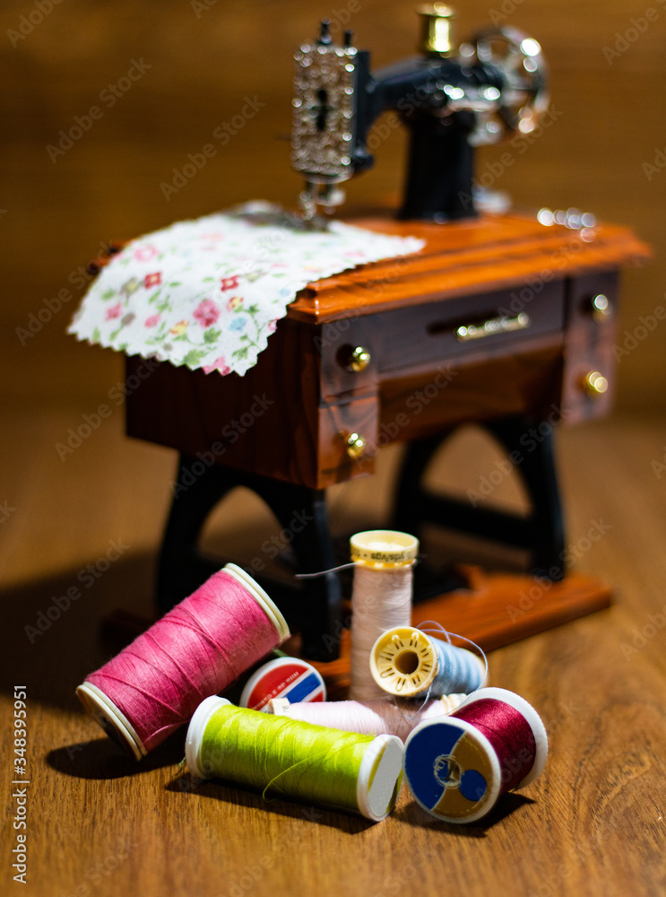 Fototapeta premium Mini sewing machine with multi-colored threads around it