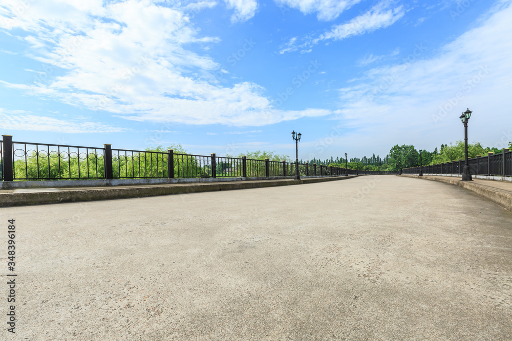 Cement road pavement and green tree under blue sky. Cement road pavement and green tree under blue sky.