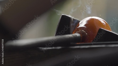 Marvering a red, smoky molten glass on a metal counter, slow motion, craftsmanship
 photo