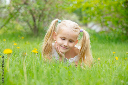 Small beautiful child girl is lying on the green grass in summer on a Sunny day