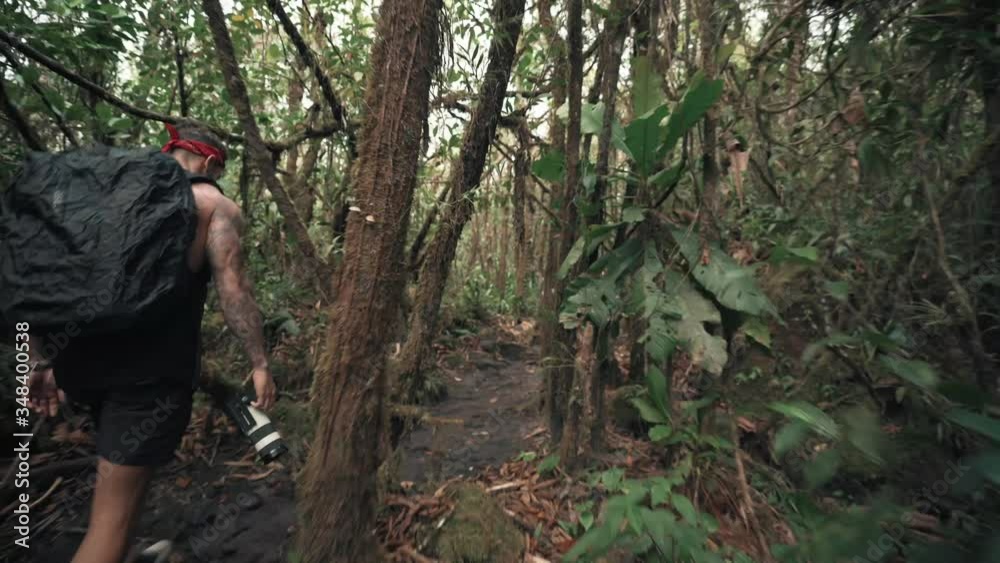 A Man With Backpack And Camera Walking In The Jungle - closeup shot A Man With Backpack And Camera Walking In The Jungle - closeup shot