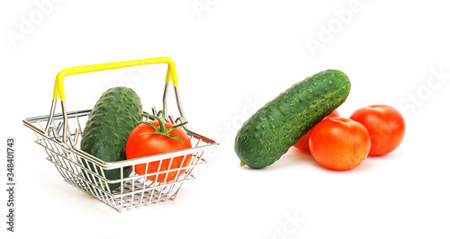 a small shopping basket with vegetables, tomato and cucumber on a white background.