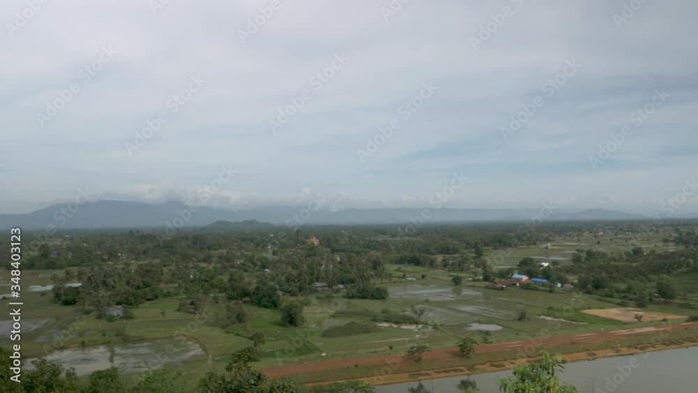 Panning shot of beautiful rural landscape of Cambodia with green fields,mountain and lake during cloudy day Panning shot of beautiful rural landscape of Cambodia with green fields,mountain and lake during cloudy day
